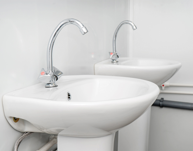 The photo of a white clean sink with the crane in the bathroom